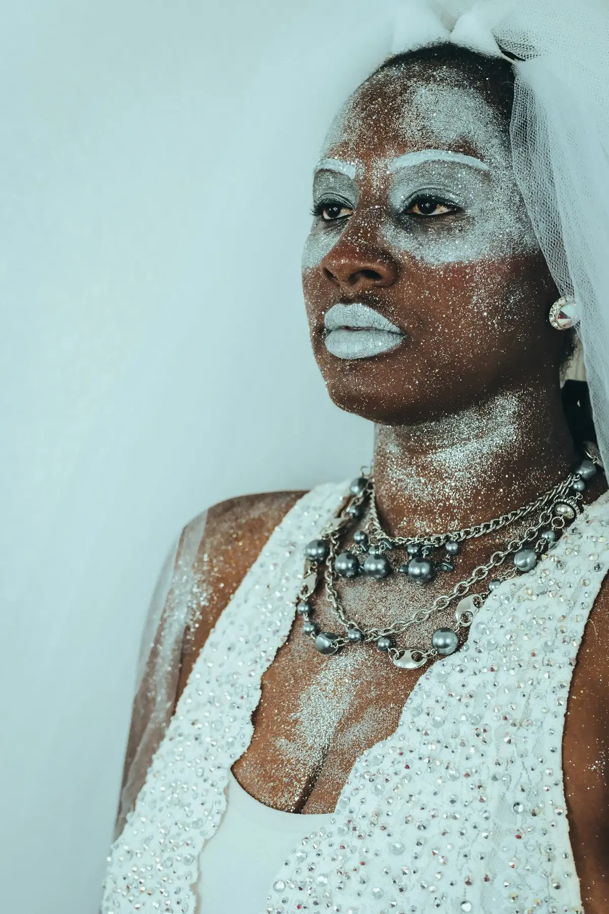 Portrait with silver glitter across the skin and chrome chain necklace