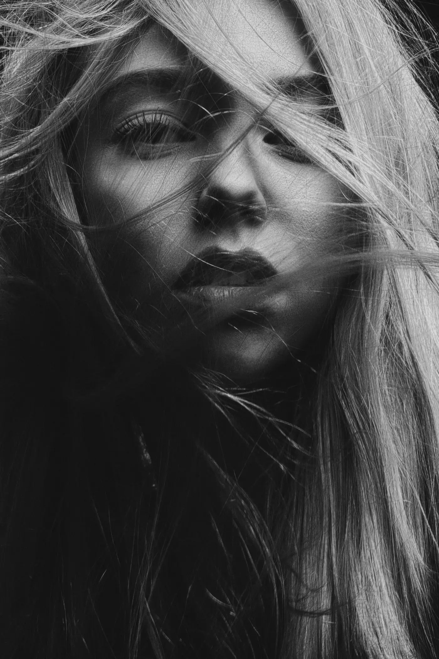 Monochrome portrait, hair blown across the face in studio wind